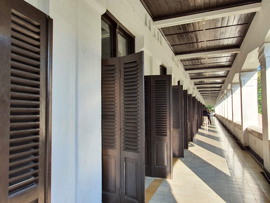 Lange galerij met houten luiken en open deuren in Lawang Sewu in Semarang.