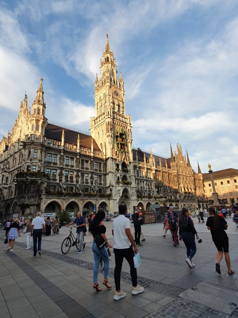 Het Neues Rathaus op de Marienplatz tijdens het gouden avondlicht, met bezoekers op het plein.