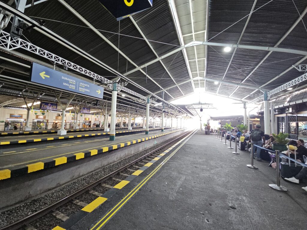 Perron van station Tugu Yogyakarta met wachtende reizigers en spoorlijnen voor vertrek van de trein naar Surabaya.