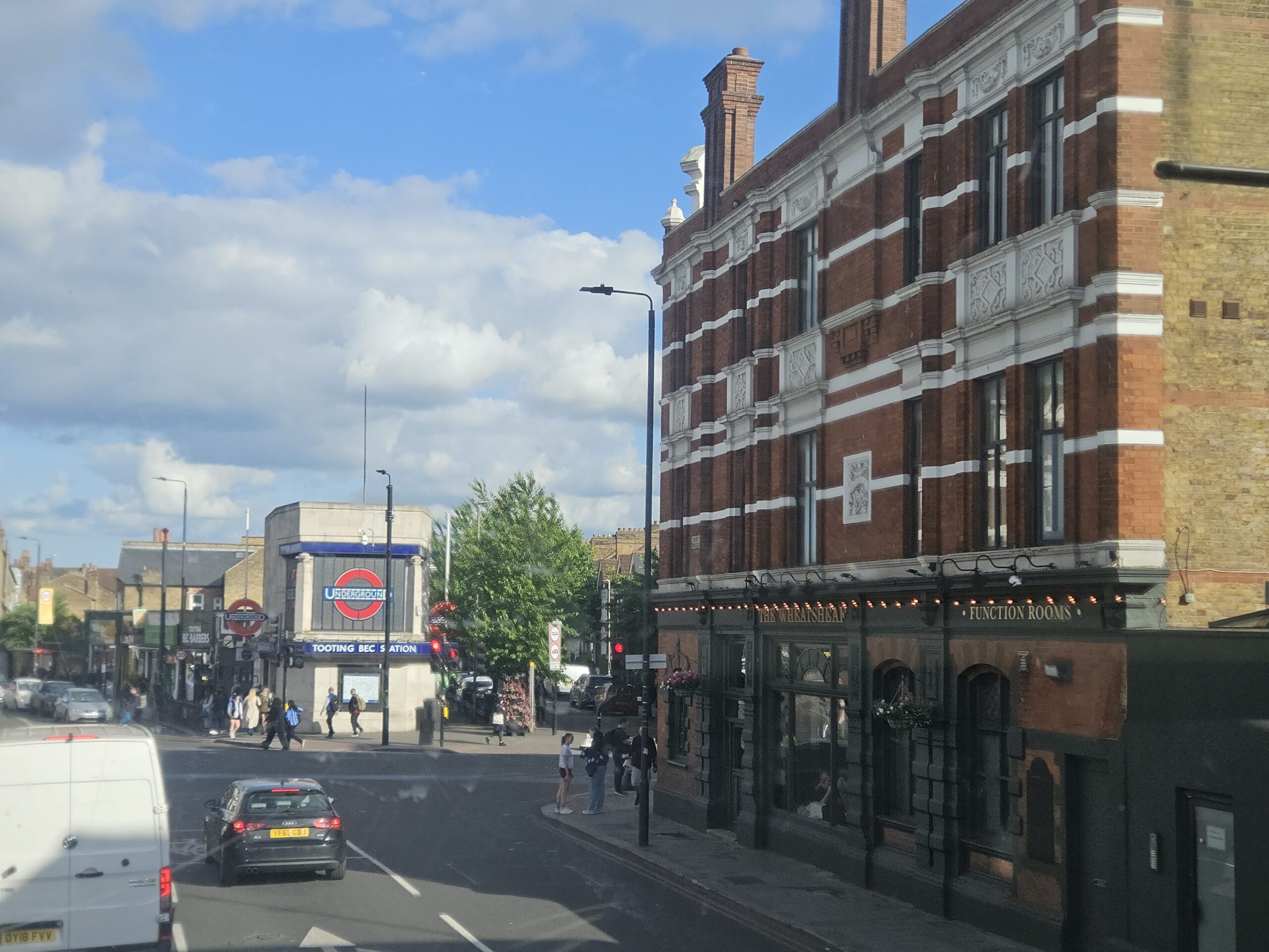 Rode dubbeldekkerbus rijdt door een straat in Zuid-Londen, gezien vanaf de bovenverdieping van een andere bus