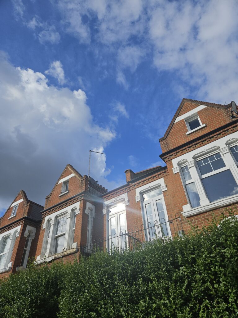 Victoriaanse rijhuizen in Tooting, Zuid-Londen, onder een blauwe lucht met voorbijtrekkende wolken.