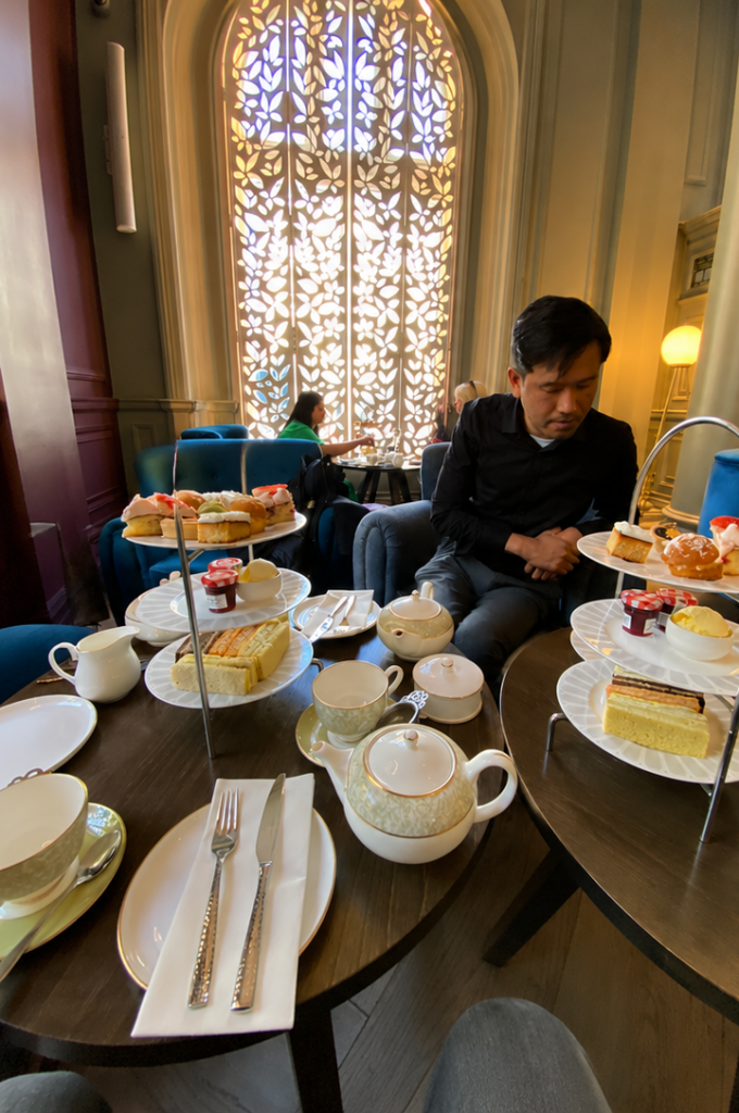 Een bezoeker geniet van een traditionele afternoon tea in een stijlvolle Londense theesalon.
