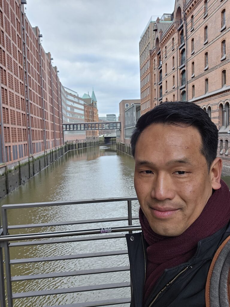 Selfie op een brug in de Speicherstadt met historische pakhuizen en een gracht op de achtergrond.