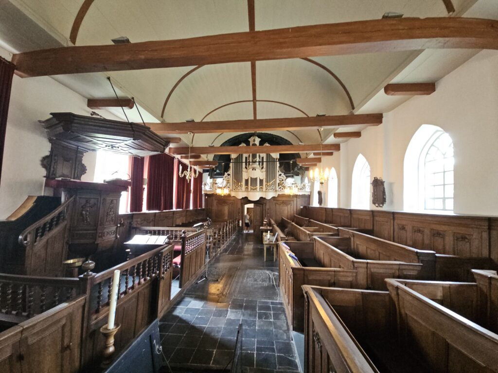 Interieur van de Hervormde Kerk in Wiuwert met houten kerkbanken en preekstoel.